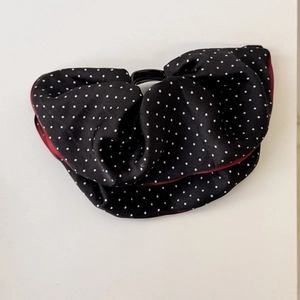 Close-up of a stylish black and red polka dot fabric hair accessory with a round buckle