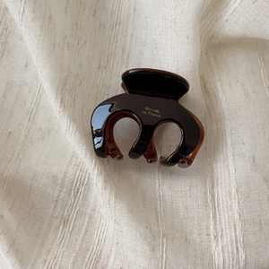 Close-up of a dark brown acetate hair claw featuring golden Barrette La France lettering