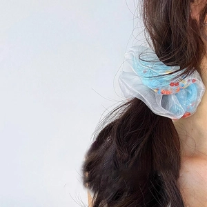 Chouchou en organza bleu et blanc avec perles colorées porté sur un chignon de cheveux