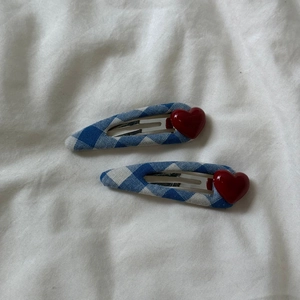 Détail de barrettes à carreaux bleu et blanc avec une breloque cœur rouge brillant en 3D