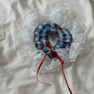 Détail d'un chouchou à carreaux avec motifs cerises et bordure en dentelle fleurie