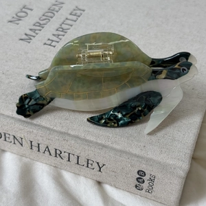 Détail du clip à cheveux tortue de mer en acétate avec une texture de marbre doré