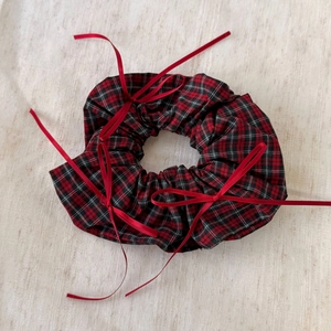 Detail of red and black plaid scrunchie with delicate ribbon bows and cotton texture
