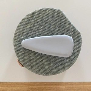 Detailed view of light gray glossy patent leather hair clip on denim textured base