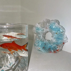 Détail d'un chouchou en organza bleu poisson rouge avec perles oranges dans l'eau