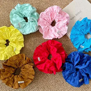 Lot de sept chouchous colorés à volants avec étiquettes de marque sur un tapis tissé