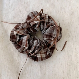 Detail of brown plaid scrunchie with delicate ribbon bows in a vintage ballet style