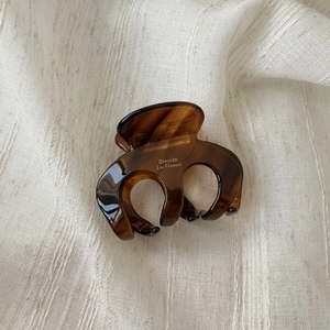 Detailed macro view of the tortoiseshell acetate hair claw on soft linen fabric background
