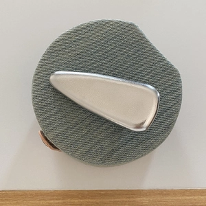 Macro detail of a silver teardrop hair clip with a matte metallic finish on denim