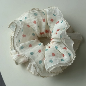 Dettaglio dello scrunchie a pois color crema con bordi in pizzo e motivi a cuoricino