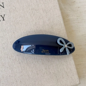 Detail view of navy blue acetate hair clip with light blue bow and rhinestone accent