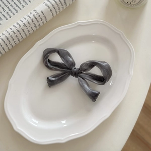 Detailed view of the gray ribbon hair clip on a vintage porcelain plate with newspaper