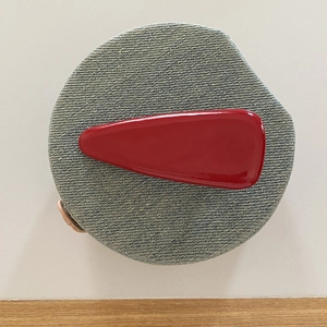 Glossy red patent leather drop hair clip displayed on blue denim texture base
