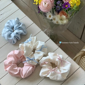Set of 4 pastel bow polka dot hair scrunchies with pearls on white wood surface