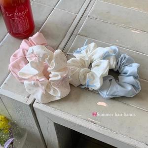 Set of four Korean style polka dot bow hair scrunchies with pearls on a stone surface