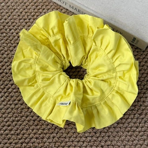 Détail du chouchou à volants jaune vif avec étiquette tissée Andrea sur le tissu