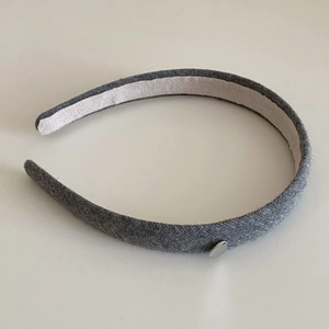 Detail of grey fabric headband with a small silver heart-shaped pendant accessory