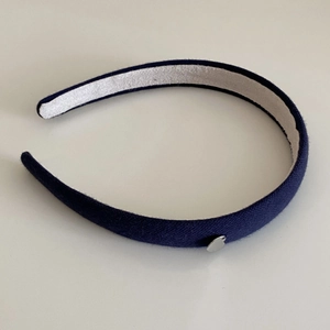 Détail d'un serre-tête en maille bleu marine avec breloque cœur et doublure