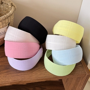 Colorful wide fabric headbands in macaron colors displayed on a wooden shelf