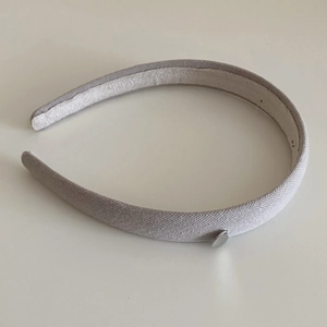 Gros plan d'un serre-tête en tissu gris clair avec un petit pendentif coeur en argent