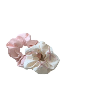Pink pleated scrunchie and polka dot bow hair tie set with pearl detail on white background
