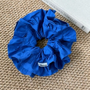 Détail d'un chouchou bleu marine surdimensionné à volants en coton avec étiquette de marque