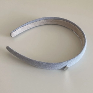 Detail of light gray knitted headband with a small silver heart-shaped metal pendant
