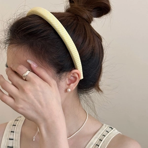 Close-up of yellow gingham headband styled with pearl necklace and silver ring on model