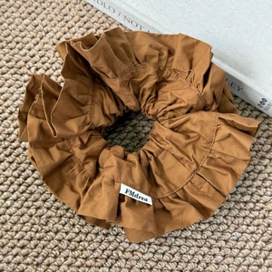 Gros plan du chouchou plissé caramel avec texture en tissu doux et étiquette cousue