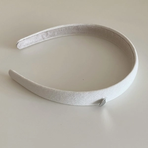 Détail du serre-tête blanc en tissu avec breloque cœur et doublure intérieure en velours