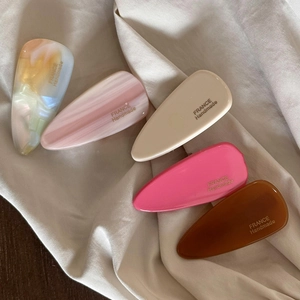 Cinq barrettes à cheveux élégantes en résine colorée sur un tissu en soie beige
