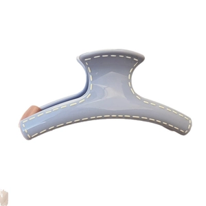 Light blue matte hair claw clip with cream hand-painted stitch details and sleek curved design