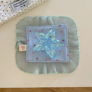 Close-up of translucent blue star-shaped hair claw clip with metal spring on decorative mat