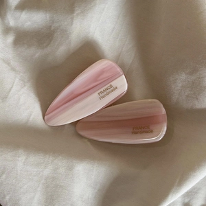 Détail de pinces à cheveux en marbre rose avec lettrage France Handmade doré