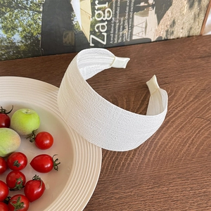 Detail of white wide headband featuring textured waffle weave fabric on wooden surface