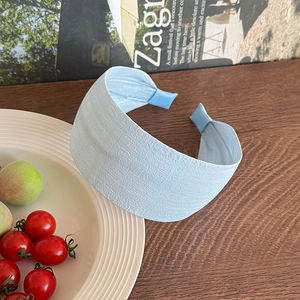 Close-up of light blue headband with textured jacquard fabric on a wooden table