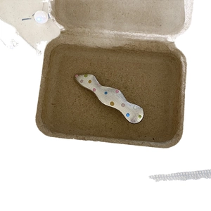 Silver brushed metal wavy hair clip with colorful polka dots in a minimalist style