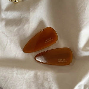 Détail de pinces à cheveux en résine ambre avec inscription dorée France Handmade