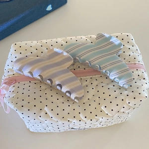Pinces à cheveux à rayures bleues et beige sur une pochette blanche à pois matelassée