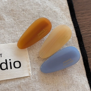 Macro detail of three waterdrop-shaped resin hair clips with France Handmade lettering