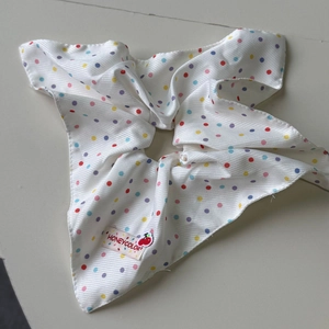 Gros plan d'un chouchou en tissu blanc à pois colorés et étiquette de marque cerise