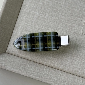 Detail of green plaid hair clip with smooth acrylic finish and shiny metallic silver clasp