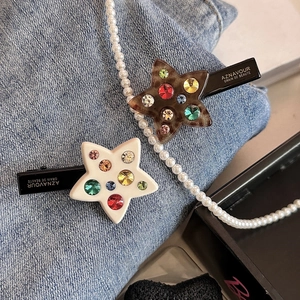Star hair clips with colorful rhinestones on denim background, minimalist duckbill clips
