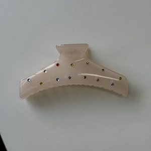 Detail of translucent nude pink large hair claw clip with colorful rhinestones