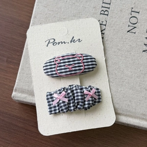 Detail of checkered and striped hair clips set with pink bear embroidery and bow
