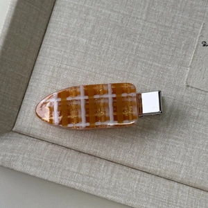 Detailed view of an orange and white checkered hair clip with gold glitter finish