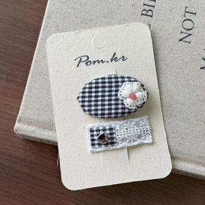 Close-up of black and white plaid hair clips with lace flowers and metal heart detail
