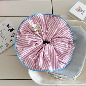 Détail d'un chouchou rayé rose à pois rouges et bordure bleue dans un plat en céramique