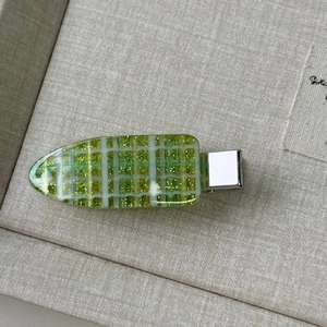 Macro shot of green checkered hair clip with fine glitter detail and silver metal base