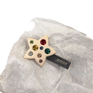 Star-shaped duckbill hair clip with colorful crystals on a matte grey base accessory